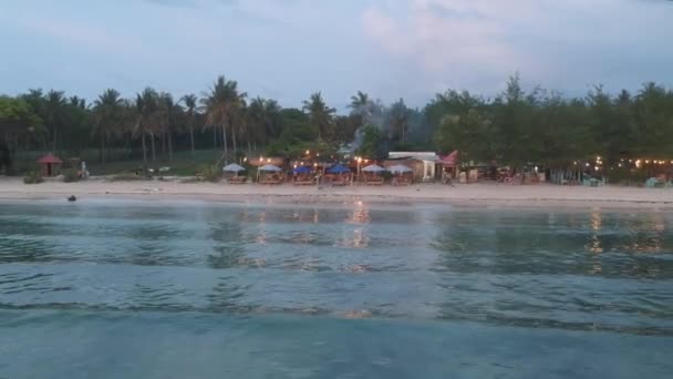 Avgång på en drönare från stranden på kvällen och med ljuset från ett café och snår av djungeln gili luft indonesien — Stockvideo