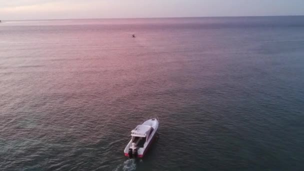 Білий човен пливе на тлі яскравого заходу сонця, відбитого у воді. — стокове відео