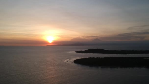 Landing twee ovale eilanden in de oceaan en de Agung vulkaan is zichtbaar op de achtergrond bij zonsondergang — Stockvideo