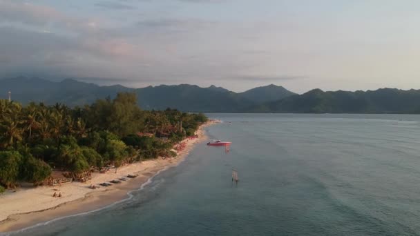 絵のように美しい山の見えるビーチを背景に美しい夕日の間に島から出発 — ストック動画