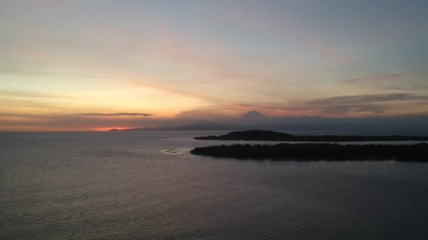 Aterrizaje de dos islas ovaladas en el océano y el volcán Agung es visible en el fondo al atardecer — Vídeo de stock