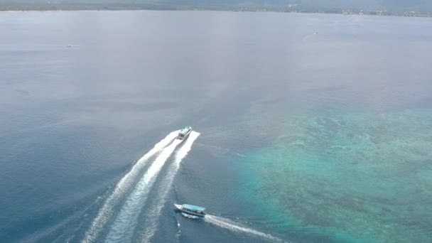 Большая лодка быстро плывет по синей океанской воде с большим отпечатком ноги вокруг подводного рифа — стоковое видео