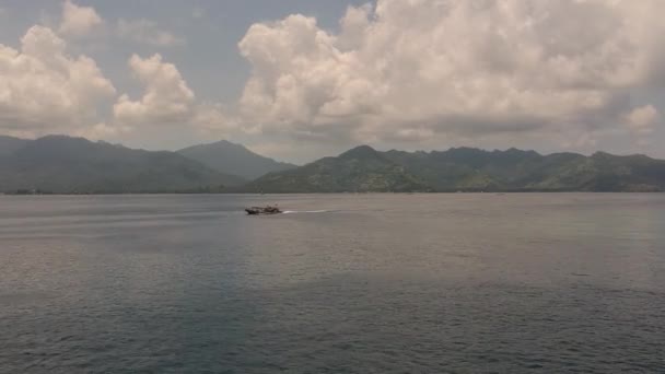 Lombok adasının dağlarının arka planına karşı okyanusta seyreden büyük bir tekne. — Stok video