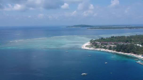 Drohne fliegt bei sonnigem Wetter über Gili Air Island, ein großes Hotel und ein Korallenriff sind zu sehen — Stockvideo