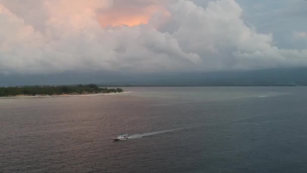 Лодка отправляется с острова с красивыми облаками и материк виден на горизонте — стоковое видео