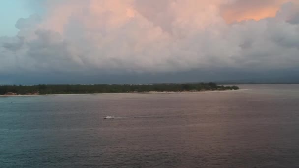 Um barco parte da ilha com belas nuvens azul-alaranjadas e o continente é visível no horizonte — Vídeo de Stock