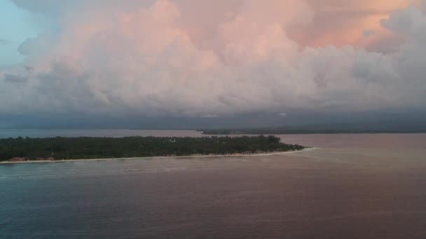 Um drone se aproxima de uma ilha com belas nuvens azul-alaranjadas, um barco flutua e o continente é visível no horizonte — Vídeo de Stock