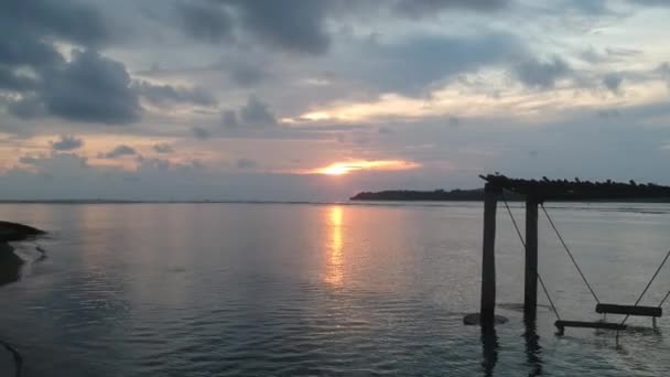 Kamera zooma över havet framåt förbi en gunga i vattnet vid solnedgången — Stockvideo