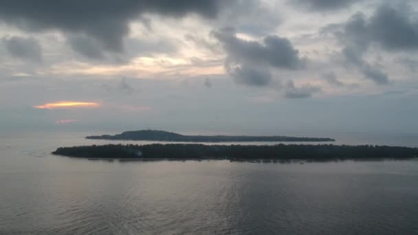 曇り空の日没を背景にジリ・メノ・トローガン島に垂直着陸 — ストック動画