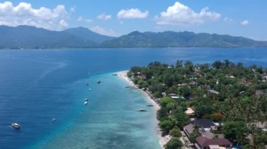 İnsansız hava aracı güneşli havada dağlarla dolu güzel bir adaya çarpıyor.