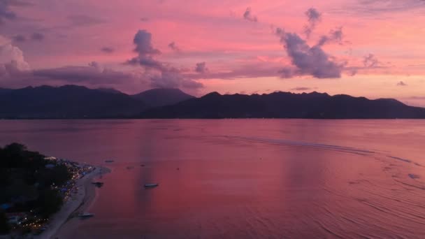 De camera vliegt terug over de oceaan bij een pittoreske zonsondergang met bergen aan de horizon gili air lombok — Stockvideo