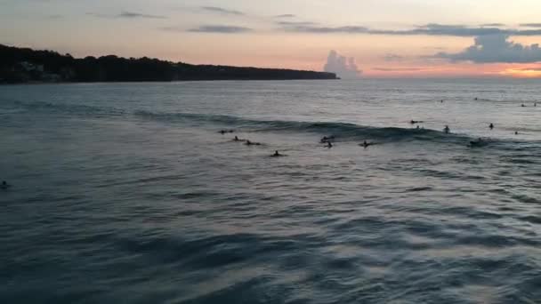 Veel surfers rijden op de grote golven van Dreamland strand bali-sia bij zonsondergang — Stockvideo