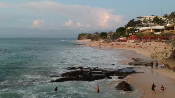 Drönare flyger längs sandhavet med stora vågor på stranden där människor går Dreamland beach bali indonesia — Stockvideo