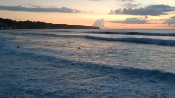 Zoom em um drone passado um surfista emergindo da água no pôr do sol praia dos sonhos — Vídeo de Stock