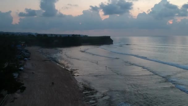 Dreamland strand drönare flygning längs stranden i skymningen människor gå på vatten bukit bali indonesia — Stockvideo