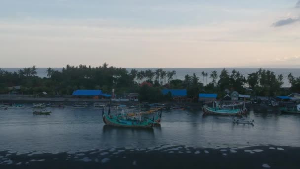 Cámara volar lejos de grandes barcos y pequeños barcos de pesca están separados por una cresta de agua Prancak Perancak oeste bali — Vídeos de Stock