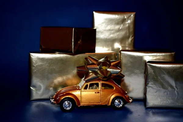 Kyiv, Ukrayna - 26 Nisan 2020: Altın araba ve hediyeler mavi arka planda sarılı altın kağıt