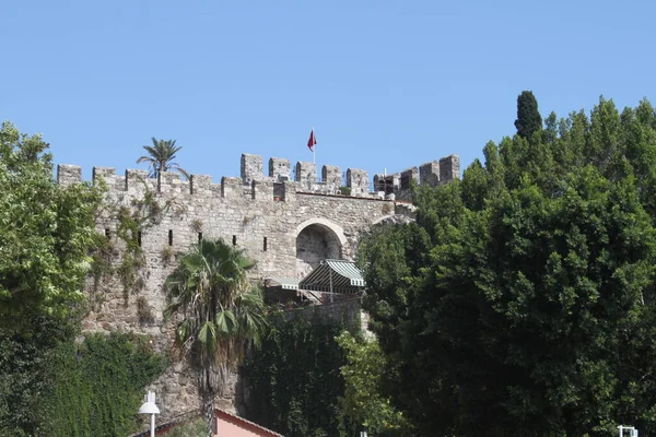 Antiguo Castillo en la Ciudad Antigua, Antalya, Turquía. Bandera turca ondeando en el viento — Foto de Stock