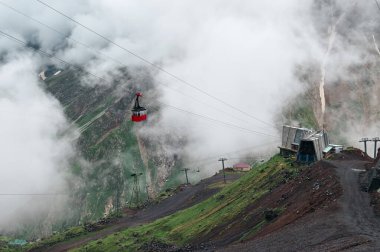 Eski kayak asansörünün parlak kırmızı kabini bulutların arasında dalgalanır.