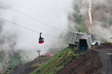 Eski kayak asansörünün parlak kırmızı kabini bulutların arasında dalgalanır.