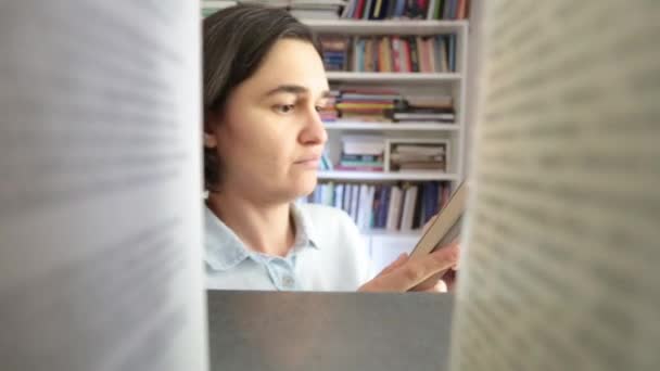 Mujer joven eligiendo libro en la biblioteca — Vídeo de stock