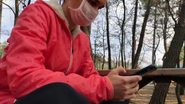 Frau mit medizinischer Maske nutzt Smartphone — Stockvideo