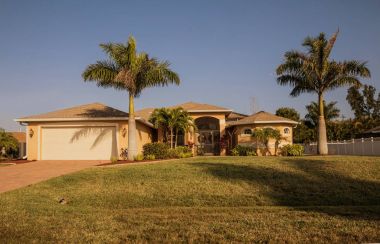 Güney Florida tek müstakil ev güneşli bir gün. Tipik Southwest Florida beton blok ve palmiye ağaçları, tropik bitkiler ve çiçekler, kırsal kesimde sıva çim çimen ve çam ağaçları. Flo