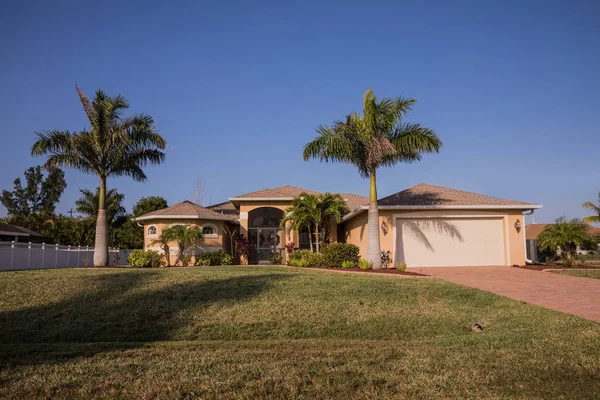 Typical Southwest Florida concrete block and stucco home in the countryside with palm trees, tropical plants and flowers, grass lawn and pine trees. Florida — Stock Photo, Image