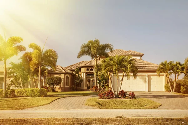 South Florida single family house in sunny day. Typical Southwest Florida concrete block and stucco home in the countryside with palm trees, tropical plants and flowers, grass lawn and pine trees. Flo — Stock Photo, Image