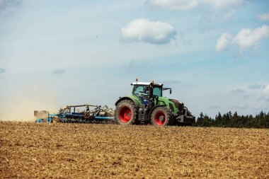 Tractor with cultivator handles field before planting clipart