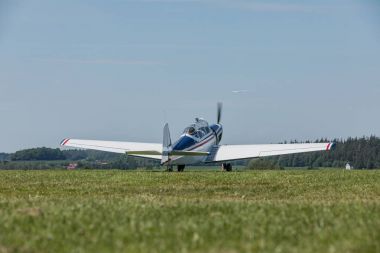 White airplane is ready to start at the grassy airfield, has a pulling yoke to pull the glider clipart