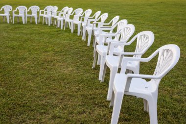 Herkesdaire oluşturacak şekilde meditasyon için düzenlenmiş bir çayır üzerinde beyaz plastik sandalyeler