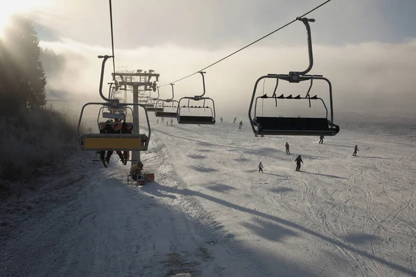 Winter bergen panorama met ski-pistes en skiliften, zonnige dag met mist en de zon stralen — Stockfoto