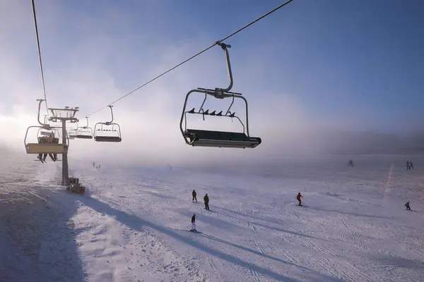 Panorama delle montagne invernali con piste da sci e impianti di risalita, giornata di sole con nebbia e raggi solari — Foto Stock