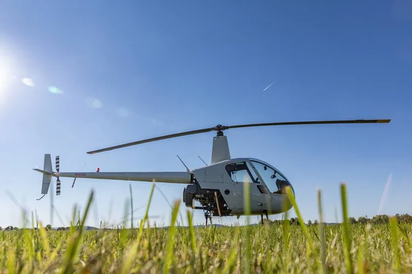 Pequeno Robinson R22 helicóptero utilitário leve estacionado no aeroporto de grama. Um dos helicópteros leves mais populares do mundo com lâminas duplas e um único motor — Fotografia de Stock