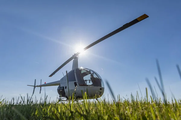 Malý víceúčelový vrtulník Robinson R22 zaparkované na trávě letiště. Jeden z nejpopulárnějších světlo na světě vrtulníky s dvojicí kotoučů a jeden motor — Stock fotografie
