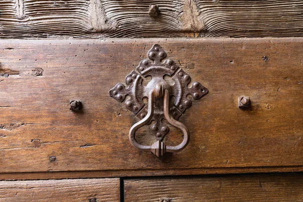 Old metal door handle knocker on a rough wooden background — Stock Photo, Image