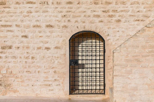 Uma treliça de metal em frente aos portões colocados em uma parede de arenito do forte — Fotografia de Stock