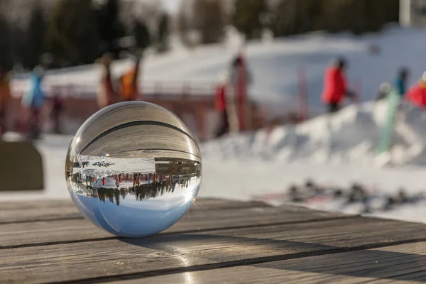 Bola de vidrio sobre una mesa de madera en las Dolomitas. Una vista a través del globo que nos rodea. Día soleado en Dolomitas. Alpe di Lusia.. Italia —  Fotos de Stock