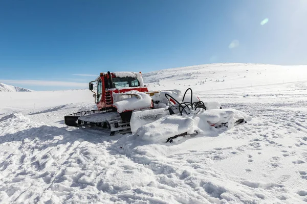 Red ratrak snowcat in winter mountains. A red snow tucker covered with snow. Royalty Free Stock Photos