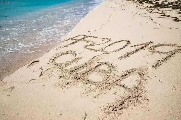 Пісочне фото написаних слів і цифр на пляжі з хвилями — стокове фото