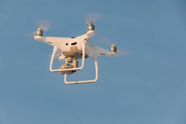 Beyaz dron Phantom mavi gökyüzüne uçan. Pervaneleri iplik ile droned yardım açılış