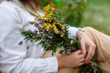 Hava harika, doğa yürüyüşü, çiçek toplama. Bir kız elinde bir buket yaz çiçeği tutuyor.