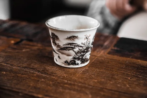 Cup on a wooden table. Ceramic cup for Chinese tea ceremony. A cup for Chinese tea. Hand painted chinese cup.
