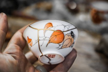 Kintsugi technique.Porcelain cup repaired with gold. clipart