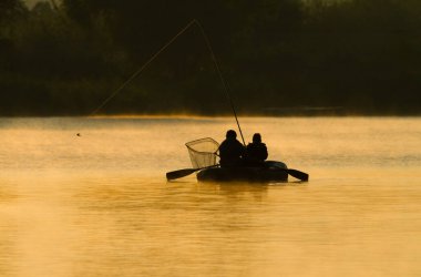 Sabah erkenden. Teknedeki balıkçılar. Nehrin üstünde buhar var. İki balıkçının silueti