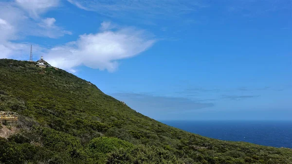 南非的开普敦 山上长满了绿色的植物 顶上有一座灯塔 乌云无边的大海 — 图库照片