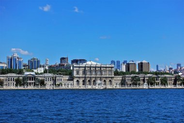 İstanbul Panoraması. Boğazın kıyısında zarif dekorasyonları ve ızgaraları olan lüks bir saray var. Modern binalar çok uzakta. Açık mavi gökyüzü.