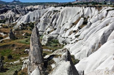 Kapadokya 'nın muhteşem manzarası. Vadi dağların beyaz katlanmış yamaçlarıyla çevrilidir. Ön planda, mantar kapağına benzer yüksek uçlu bir tepesi olan tuhaf silindirik bir kaya var. Mucize.