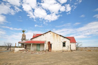Çölde terk edilmiş, terk edilmiş, mavi gökyüzü olan eski bir ev..